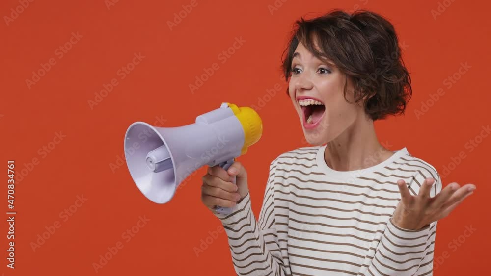 Excited vivid promoter young brunette woman 20s wears striped shirt point index finger aside scream in megaphone announces discounts sale Hurry up isolated on plain orange background studio portrait Excited vivid promoter young brunette woman 20s wears striped shirt point index finger aside scream in megaphone announces discounts sale Hurry up isolated on plain orange background studio portrait