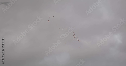 red and white balloons flying in a cloudy sky photo