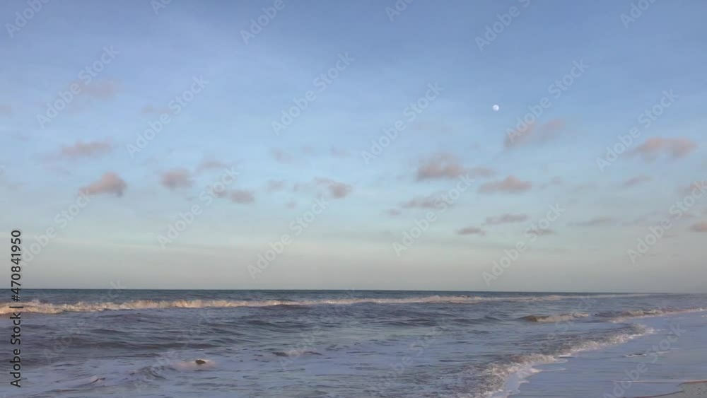 Sky and moon with waves on a sandy Caribbean Sea beach during sunset Sky and moon with waves on a sandy Caribbean Sea beach during sunset