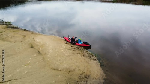  Old man tourist sit near red kayak  .Aerial 