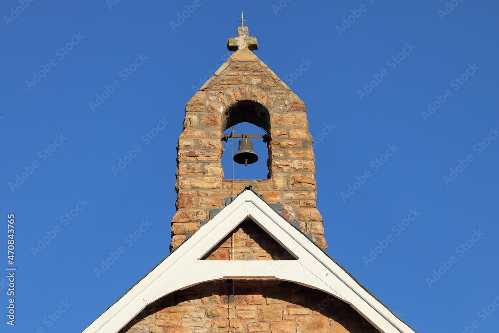 Sandstone bell tower of small chapel with blue sky. Architecture, religion, history, travel concept. Copy space.