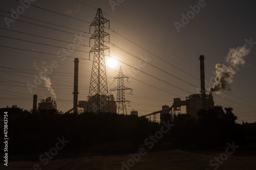 Coal power plant with a high voltage tower and the sun behind in Ventanas Town, Chile