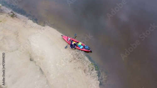 Fly up over old man tourist sit near red kayak .Aerial 