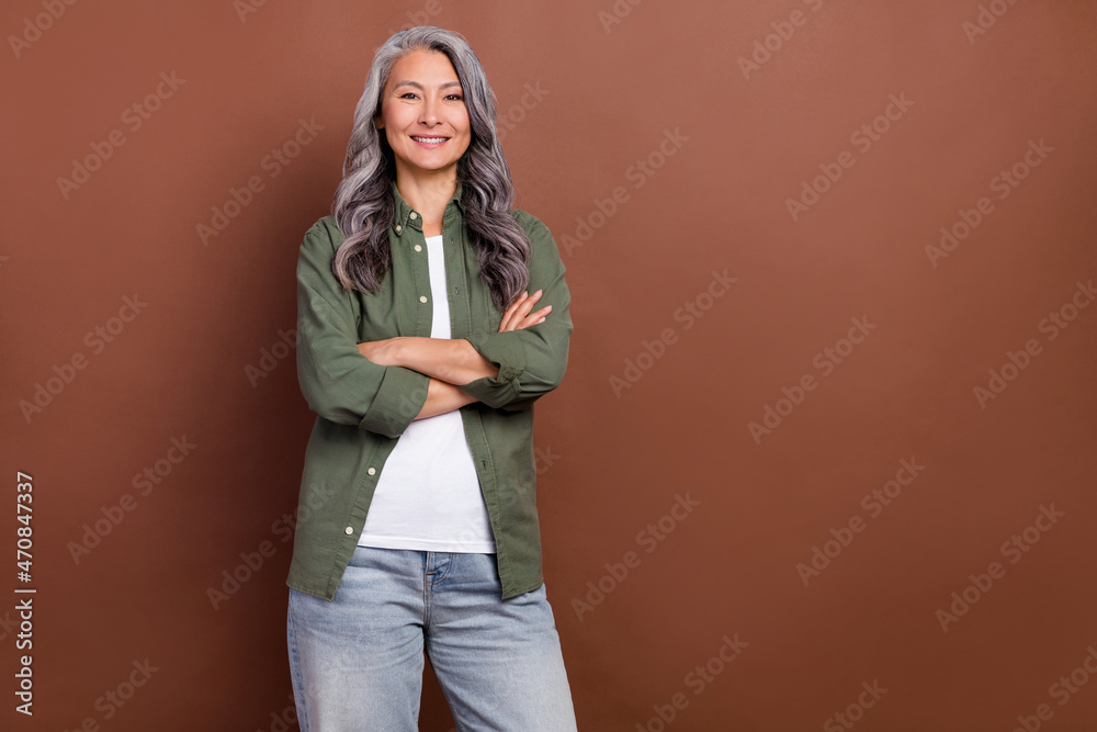 Photo of boss aged grey hairdo lady crossed arms wear khaki shirt jeans isolated on brown color background Photo of boss aged grey hairdo lady crossed arms wear khaki shirt jeans isolated on brown color background