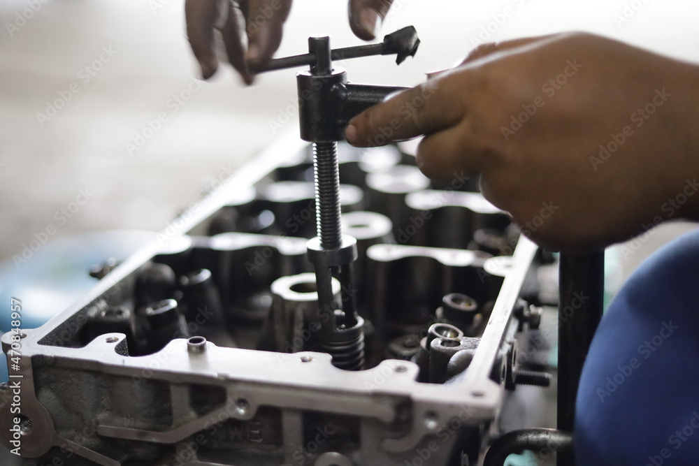 the hand of a mechanic is installing the valve seal of an overhauled car engine the hand of a mechanic is installing the valve seal of an overhauled car engine