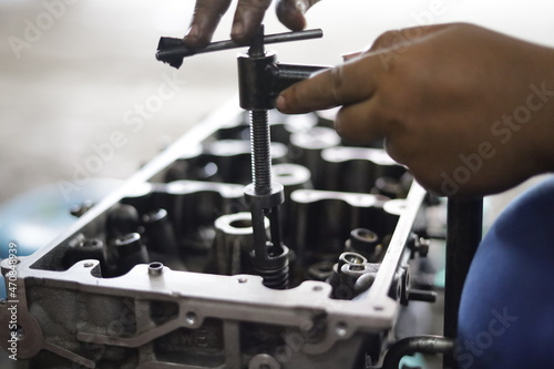 the hand of a mechanic is installing the valve seal of an overhauled car engine photo