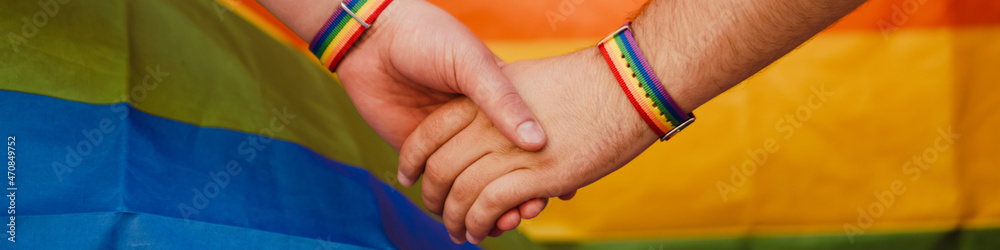 Young gay couple with rainbow flag holding hands together during Stock ...