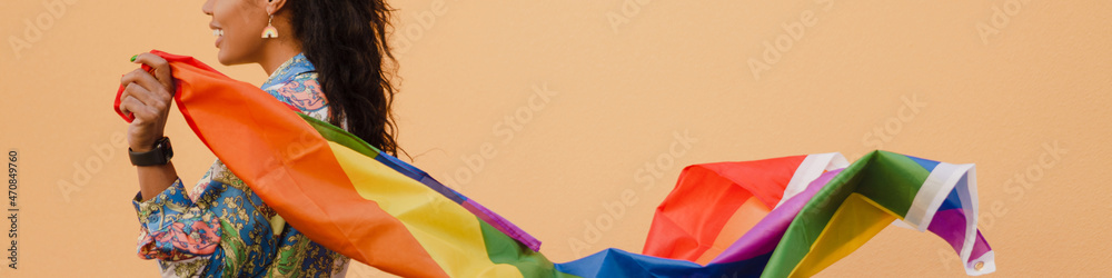 Fototapeta premium Black woman with rainbow flag smiling and looking aside
