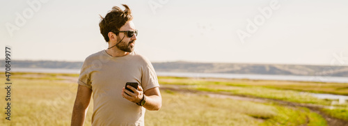 White bristle man using mobile phone during hiking outdoors