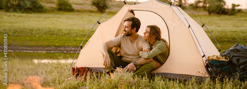 White couple hugging and sitting in tent during camping together