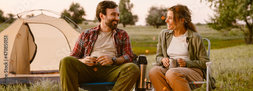 White couple smiling and drinking tea during camping together