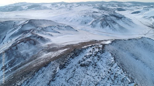 Aerial forward Epic winter snow-covered mountain tundra Buryatia, Siberia abstract natural landscape. Roads through wild untouched terrain, off-road. Hills shaman's way. Reserve. Open space, horizon photo