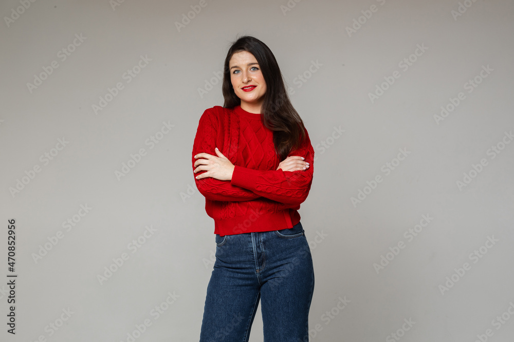 cheerful woman in warm red sweater and blue jeans crosses her hands on the chest cheerful woman in warm red sweater and blue jeans crosses her hands on the chest