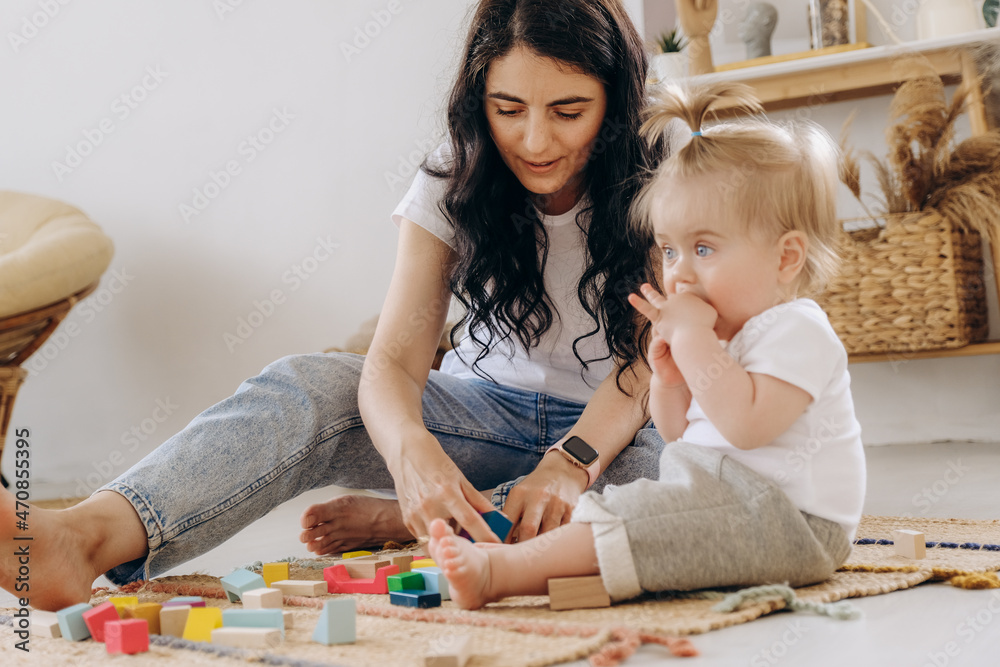 Fototapeta premium Communication between mother and child. Love and kindness in the family. The kid plays with wooden eco-friendly toys.