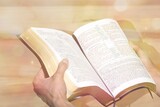 Human hand  prays while reading the open bible, on wooden table