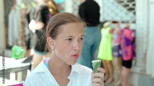 Portrait teenage girl eating ice cream. Happy child eating delicious ice cream outdoor. Girl looks at camera and smiles. Sunny summer day.
