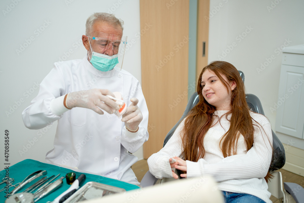 Senior dentist try to entertain and talk with young girl to relax during treatment process in dental clinic. Senior dentist try to entertain and talk with young girl to relax during treatment process in dental clinic.
