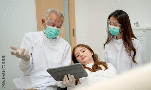 Senior dentist explain the procedure to young girl to relax during treatment process in dental clinic.