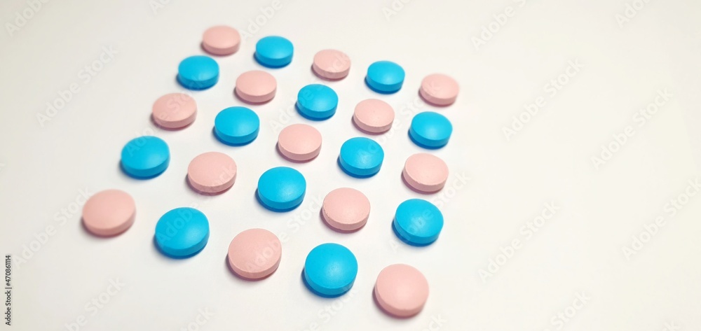 Pink and blue pills on a white background. Tablets for treatment without packaging. Useful vitamins for immunity.