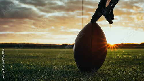 American Football Kickoff Game Start. Close-up Shot of an American Ball Standing on a Grass Field Held by Professional Player. Preparation for Championship Game.