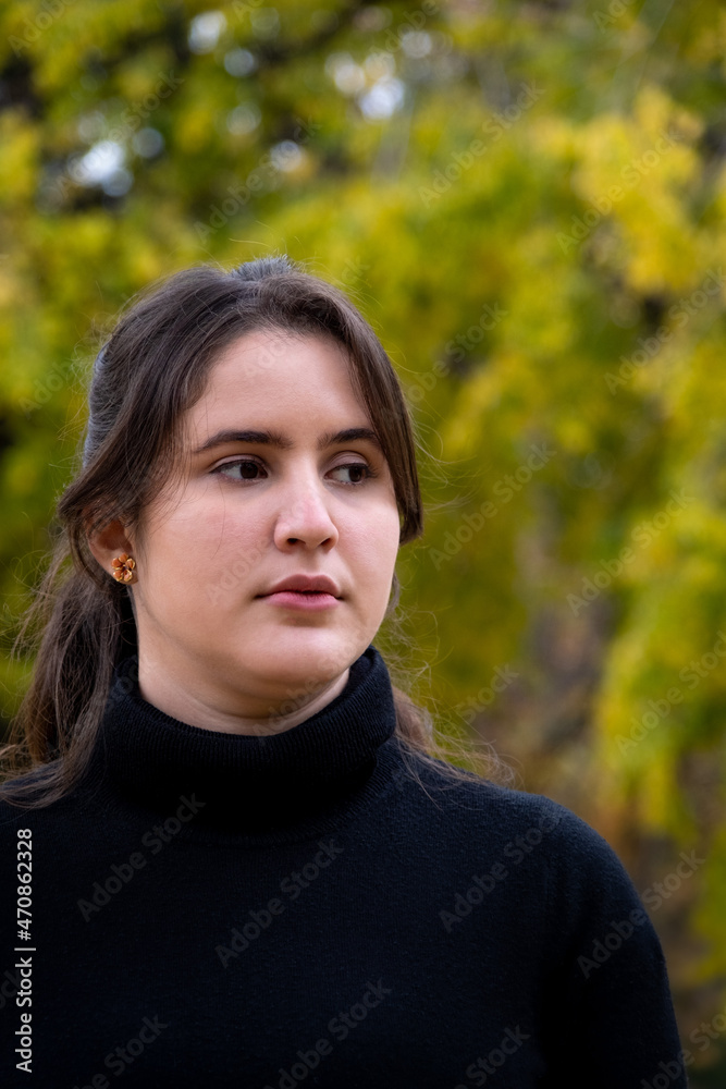 Portrait of a beautiful brunette woman wearing a black sweater and looking aside. Young european caucasian brunette woman outdoors Portrait of a beautiful brunette woman wearing a black sweater and looking aside. Young european caucasian brunette woman outdoors