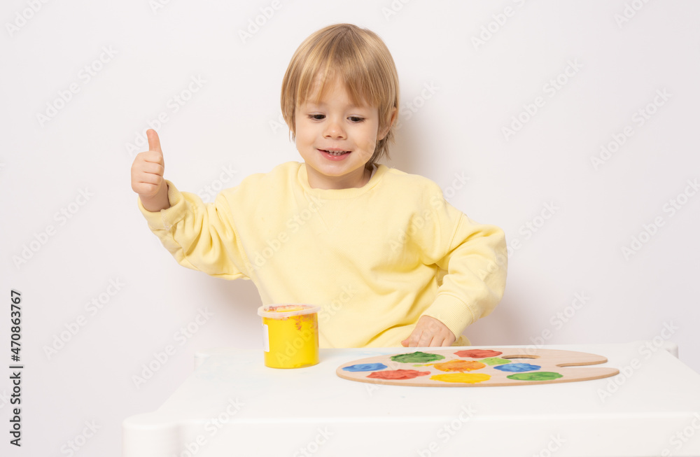 Inspired little boy at the table drawing with thumb up isolated on white Inspired little boy at the table drawing with thumb up isolated on white