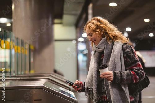 Young woman checking out at metro station using mobile phone
