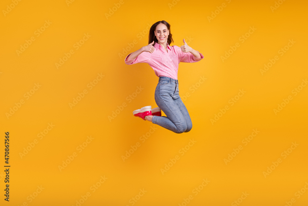 Full size profile side photo of young pretty girl have fun jump show thumb-up advertise approve isolated over yellow color background Full size profile side photo of young pretty girl have fun jump show thumb-up advertise approve isolated over yellow color background