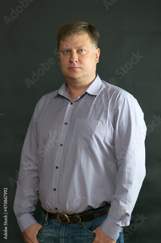 Adult tall blonde 40 years old in a strict shirt on a black background.