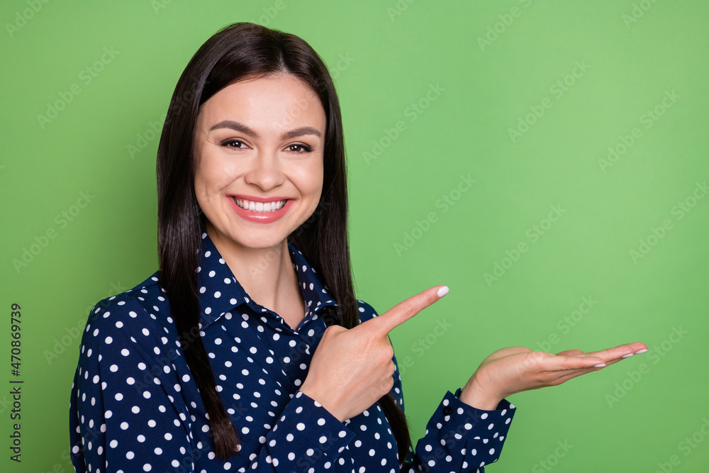 Photo of happy cheerful young woman point finger hold hand empty space object isolated on green color background Photo of happy cheerful young woman point finger hold hand empty space object isolated on green color background