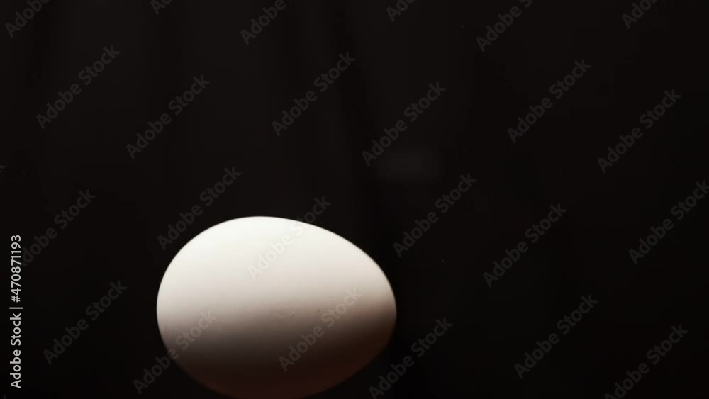 Egg is spinning on a black background. Slow motion of an egg in a shell spinning on glass. Close shot of a spinning egg. Egg is spinning on a black background. Slow motion of an egg in a shell spinning on glass. Close shot of a spinning egg.