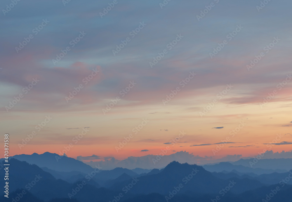 Predawn clear sunset sky with mountain layers landscape and orange horizon and blue atmosphere.