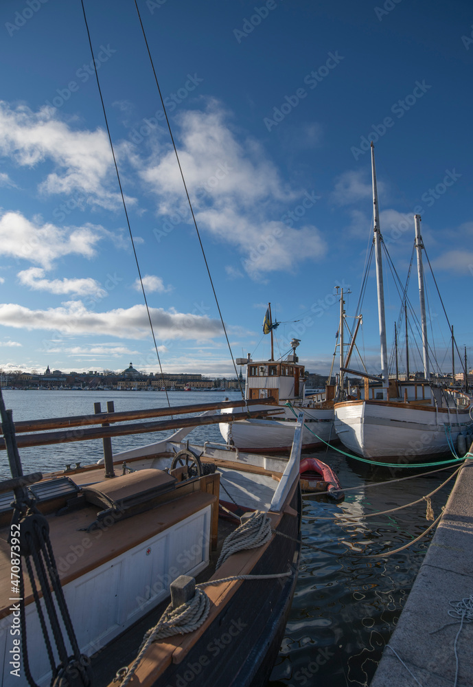 Fototapeta premium Old sailing, fishing and cargo boats at the pier Strandvägen in the bay Ladugårdsviken a color full autumn day in Stockholm