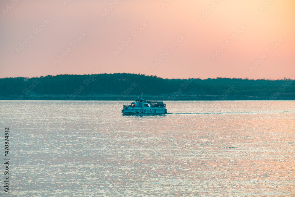 Sunset on the Amur river embankment. Passenger ship on the Amur river during sunset.