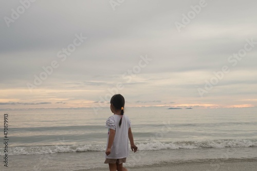 Little girl is playing on sand beach coast seashore with sunset sky for imagination and mediation and outdoor self learning concept with copy space