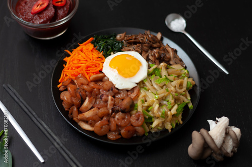 Pibimbap is a popular dish of traditional Korean cuisine made from rice, seafood, zucchini, mushrooms, carrots, spinach, eggs.