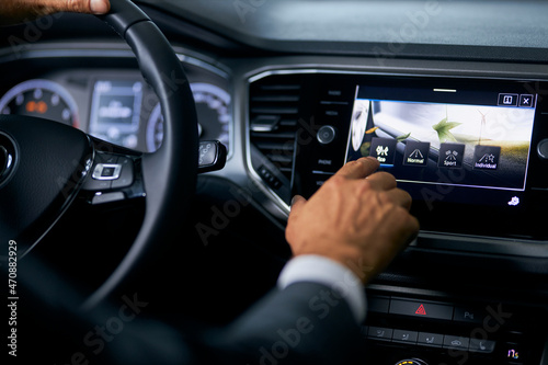 Caucasian male buyer testing electronic multimedia of modern car at showroom. Close up of male hands and digital display. Innovative technology in luxury auto. 