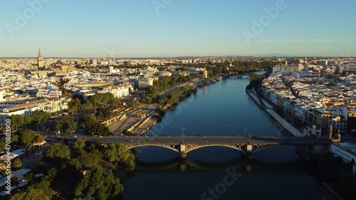 Aerial drone footage of the Seville city along the Guadalquivir canal with various landmark such as the cathedral, the Torre del Oro and the Bull area in Andalusia, Spain