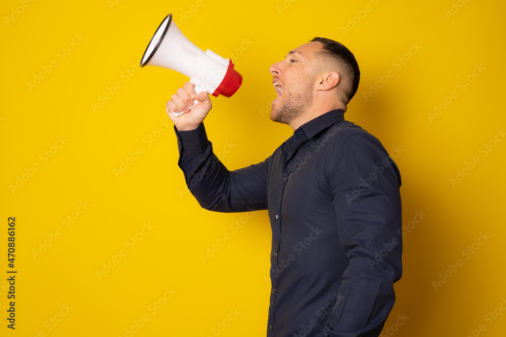 portrait of a handsome young man shouting with megaphone isolated over yellow background portrait of a handsome young man shouting with megaphone isolated over yellow background