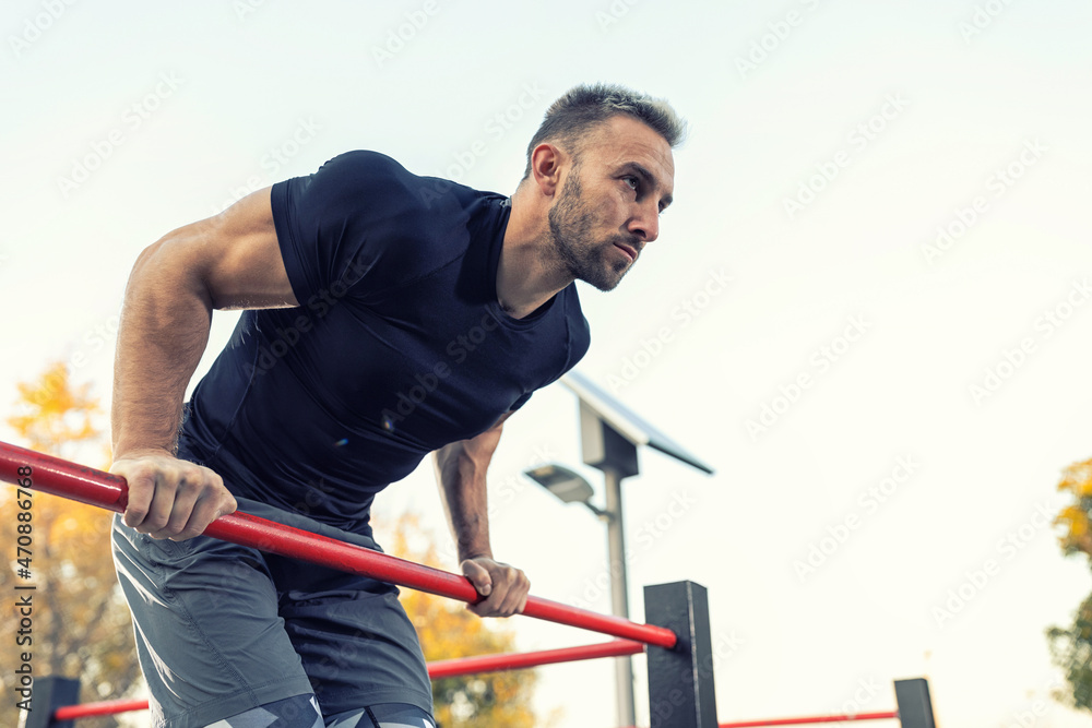 Muscular man working out using only a bar, outside working out concept Muscular man working out using only a bar, outside working out concept