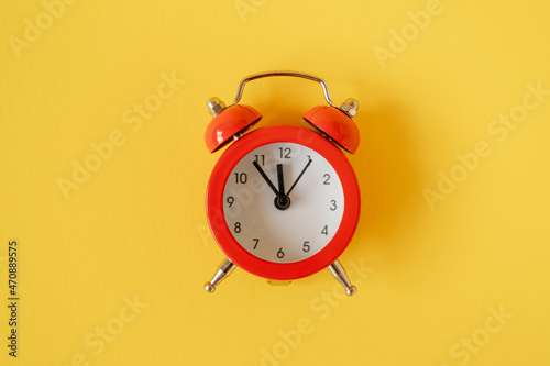Red alarm clock on yellow background.