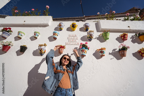 Cheerful Asian woman near wall with flowerpots photo