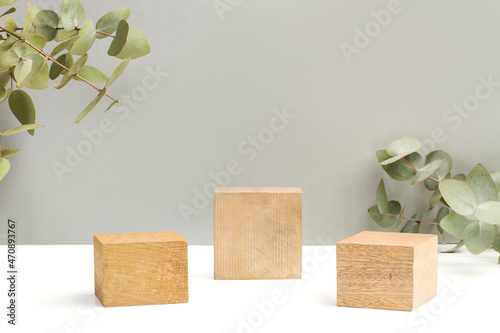 Bases podio de madera para presentación cosmética decorado con ramas de eucalipto sobre un fondo gris. Vista de frente. Copy space. Concepto: Publicidad de productos de belleza natural y spa.  photo