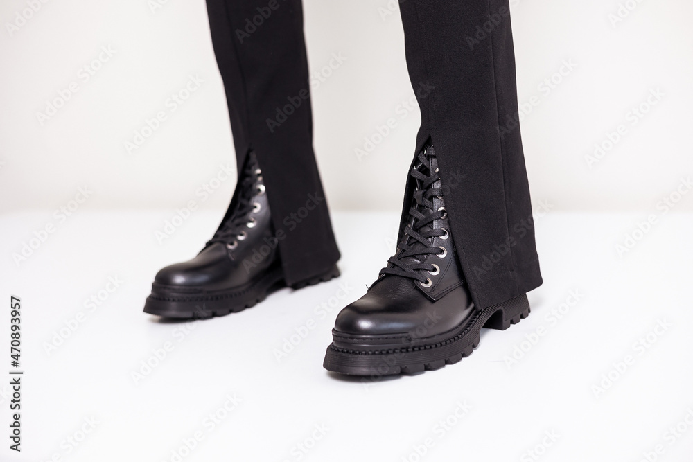 Beautiful female legs with fashionable black boots on the background in the studio. Women's stylish leather boots.