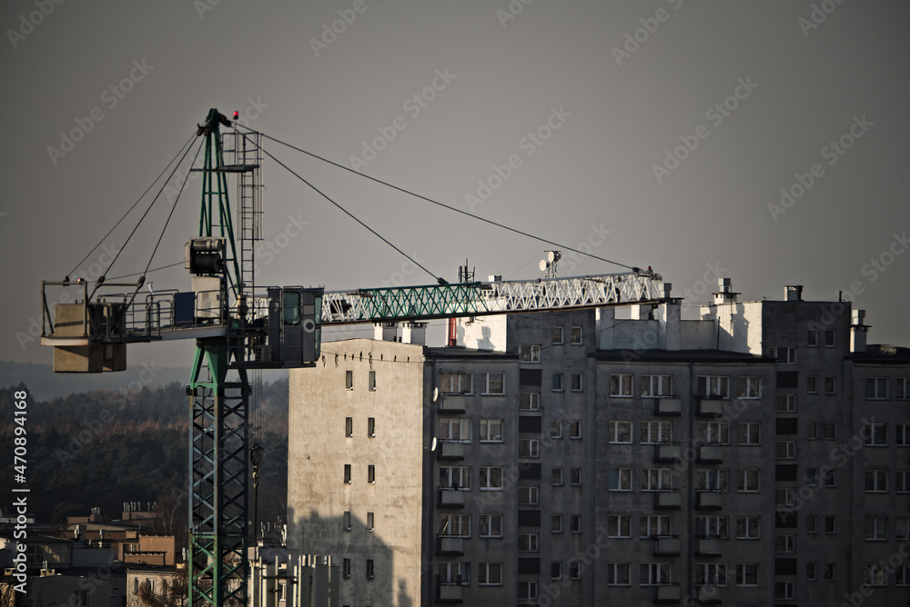 Duży dźwig budowlany (żuraw )   na tle bloku mieszkalnego . Budowa . A large construction crane  against the background of an apartment block. Building . - obrazy, fototapety, plakaty 