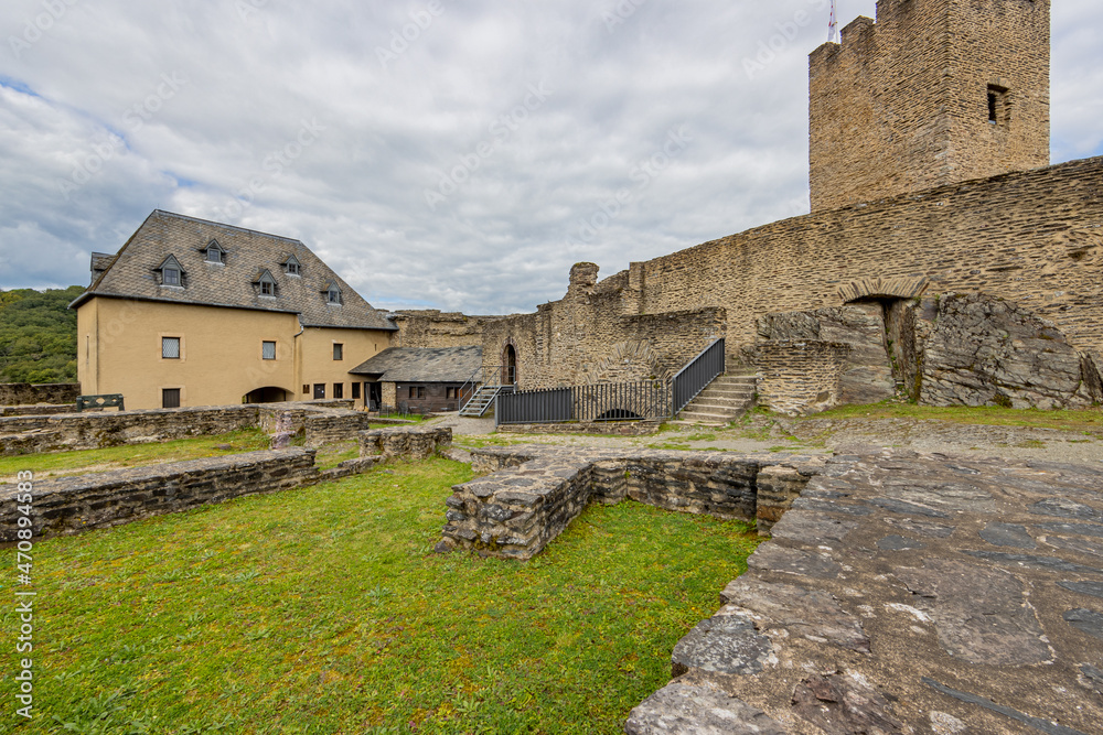 Medieval castle of Bourscheid, predominantly open air ruin with dilapidated stone walls, a tower, courtyards and green grass, cloudy day with a sky covered in gray clouds, Luxembourg