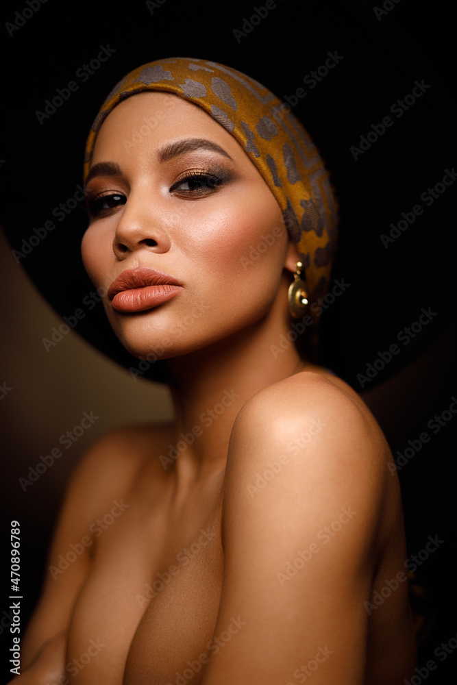 Fototapeta premium Closeup portrait of an elegant and beautiful african american young woman with perfect smooth glowing skin, full lips and fashionable makeup. Dark background. Studio shoot