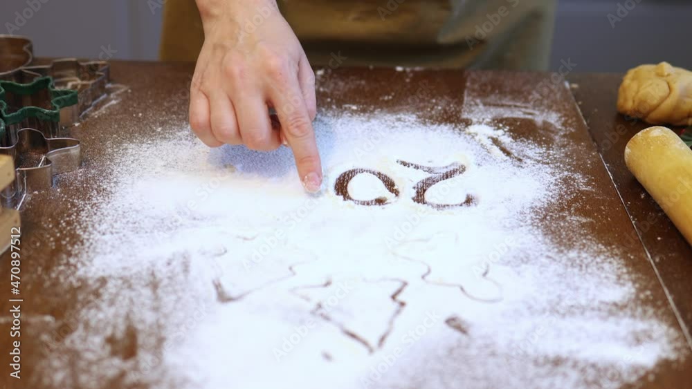 hand drawing writing 202 number on flour sifted on brown wooden table in the kitchen while preparing to cook christmas new year winter holidays cookies and biscuits. 2023 or 2024 hand drawing writing 202 number on flour sifted on brown wooden table in the kitchen while preparing to cook christmas new year winter holidays cookies and biscuits. 2023 or 2024