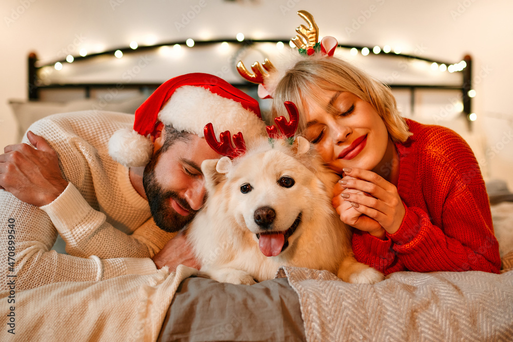 Obraz premium Couple in love for New Year and Christmas with a dog at home