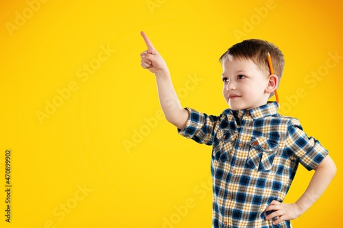 Smiling cute smart child shows fingers to empty space,